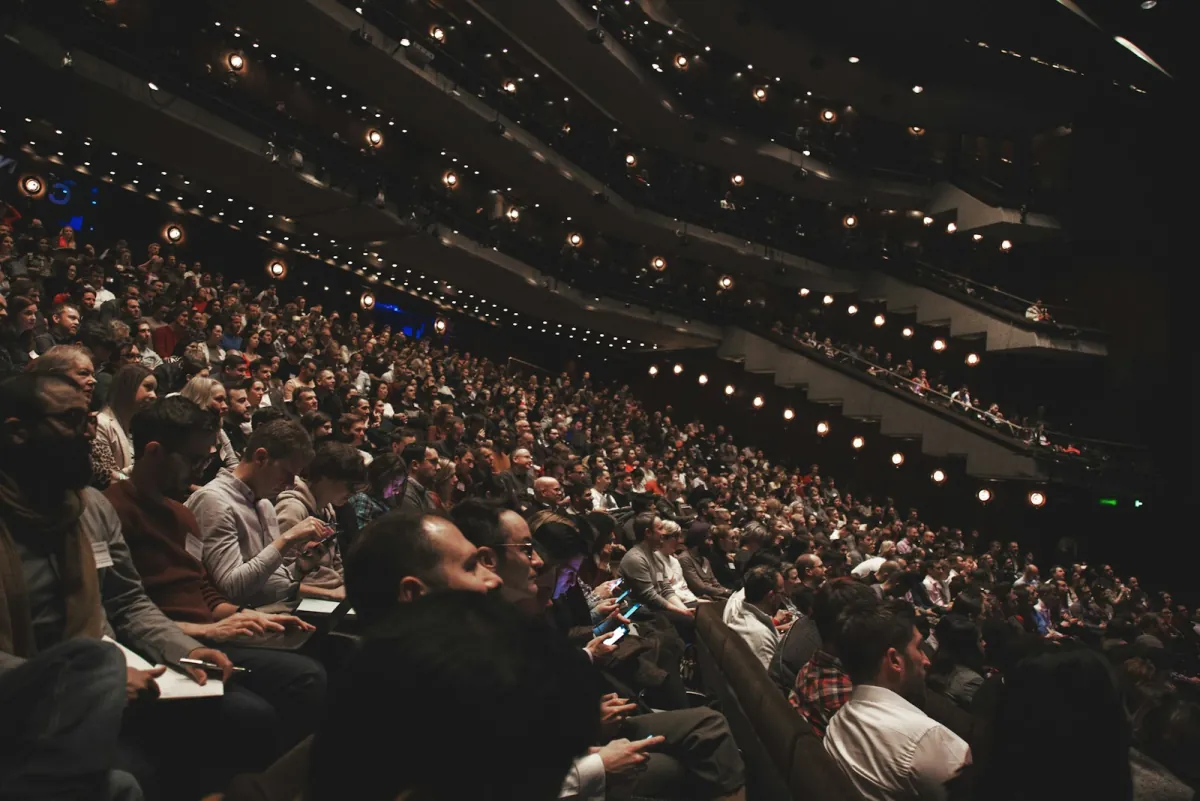 A large audience in an auditorium, each person joining a live quiz on their own phone